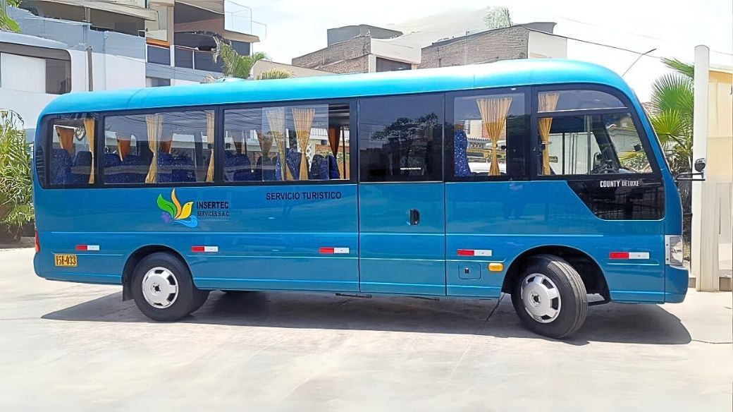 Un autobús azul está estacionado en un estacionamiento al lado de un edificio.