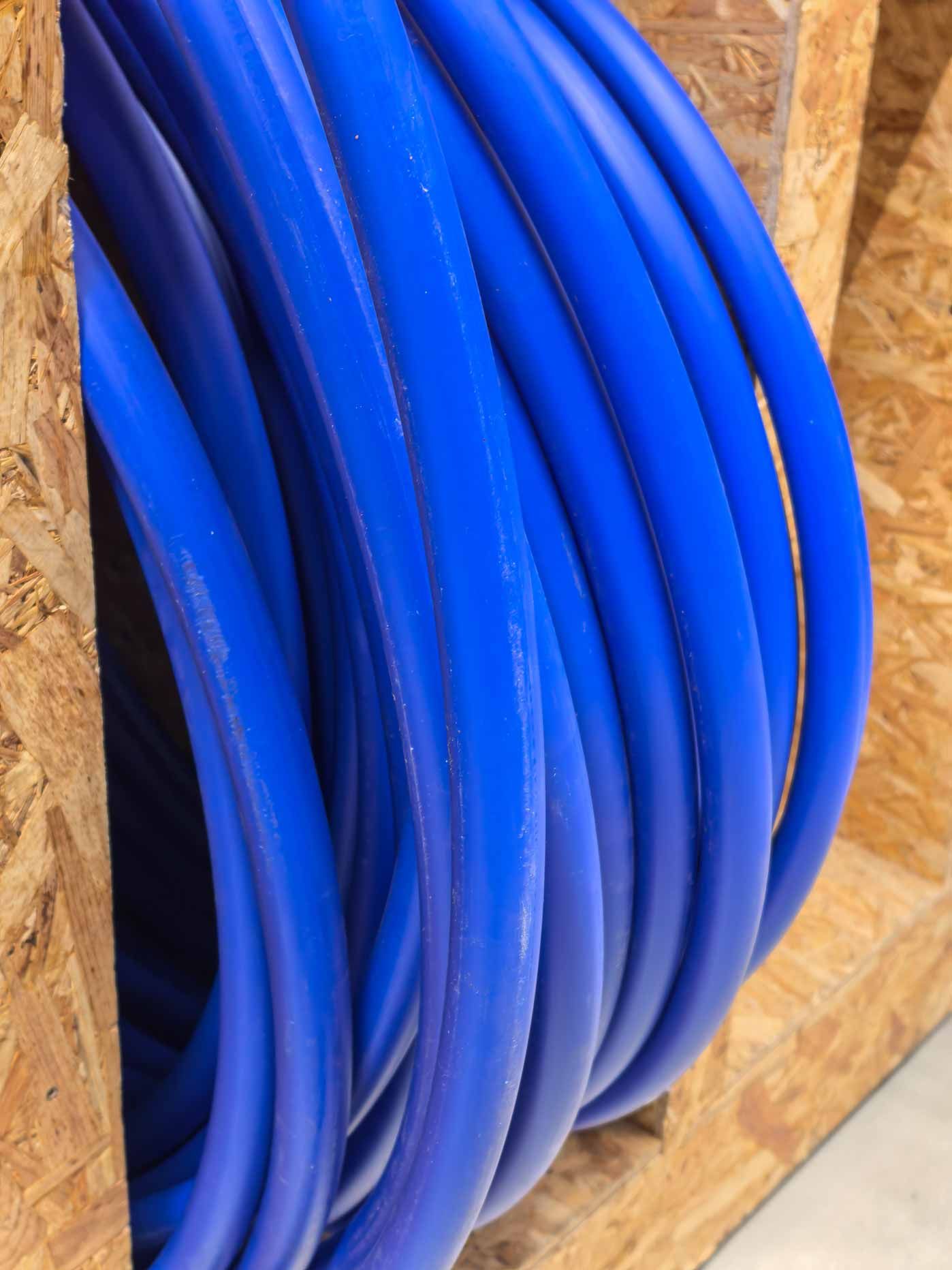 Coiled blue hoses hanging against a plywood wall