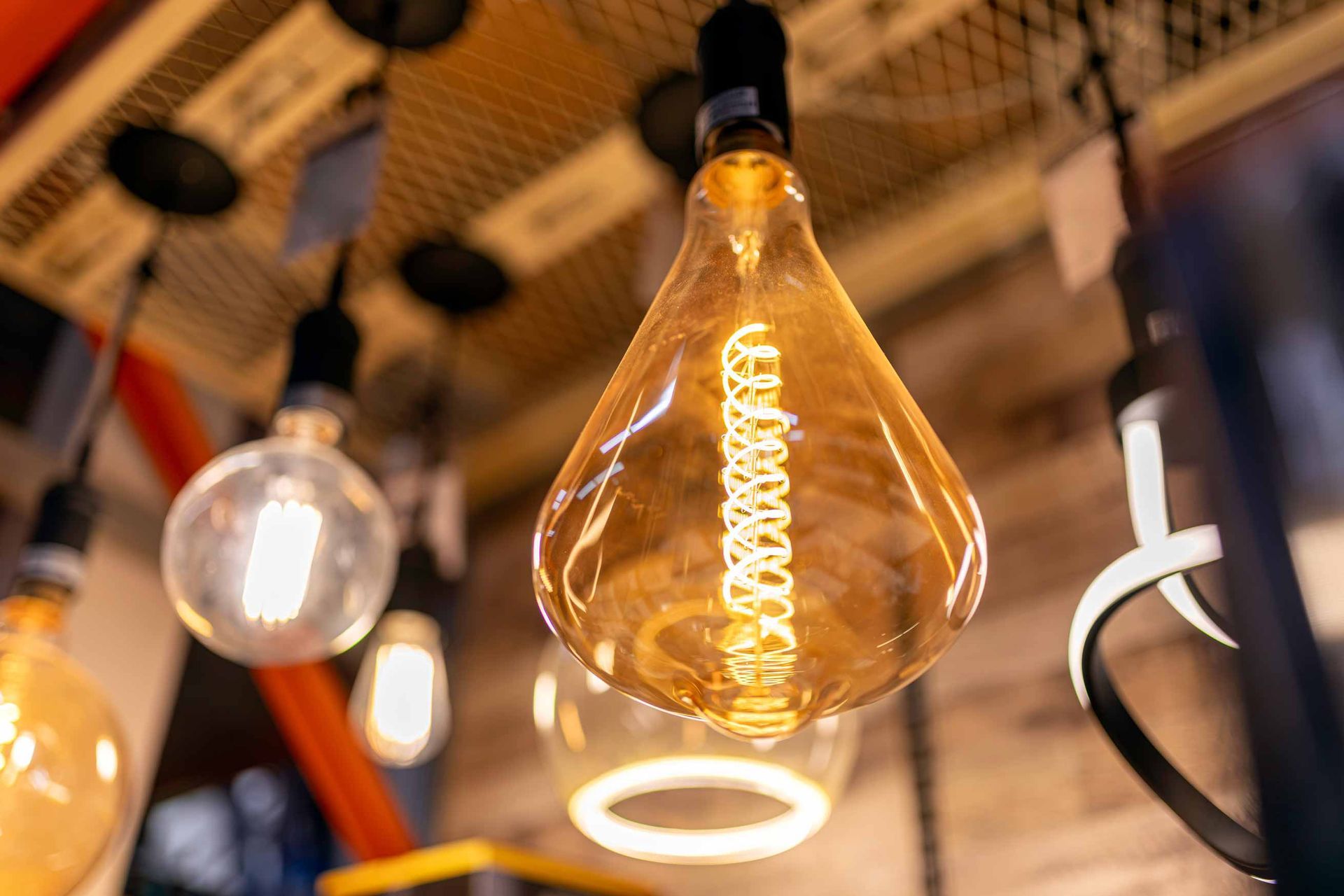 Close-up of warm glowing Edison bulbs hanging indoors with a blurred industrial ceiling.