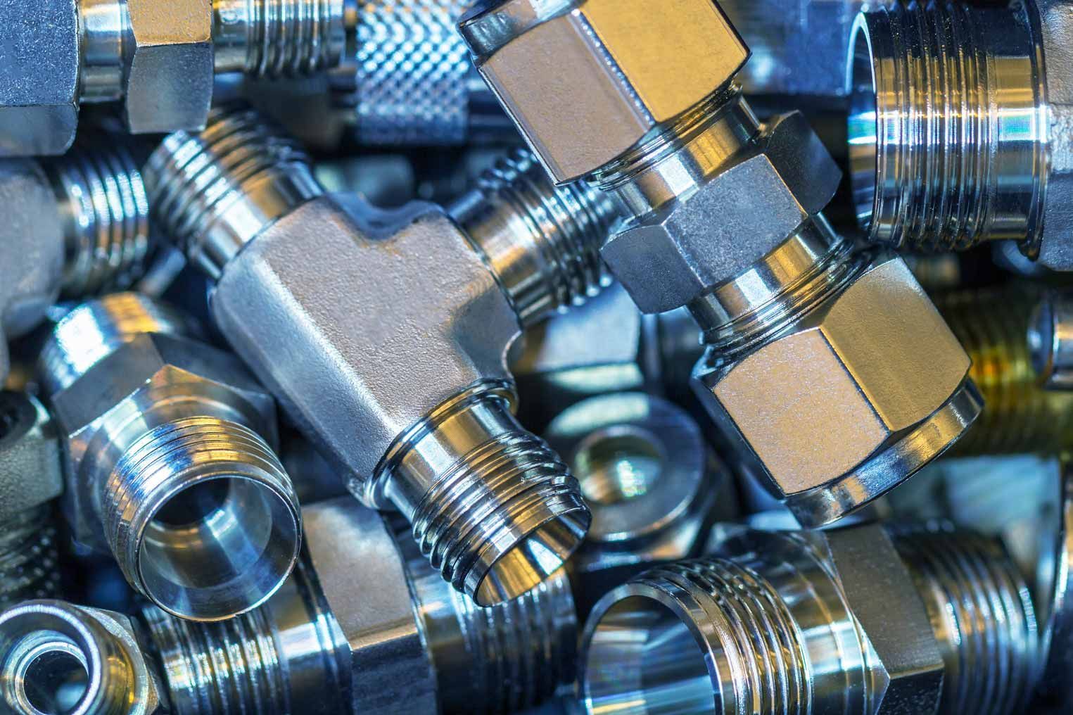 Close-up of shiny metal pipe fittings and connectors stacked together