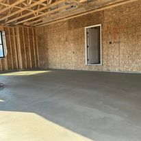 A large empty room with a concrete floor and wooden walls.