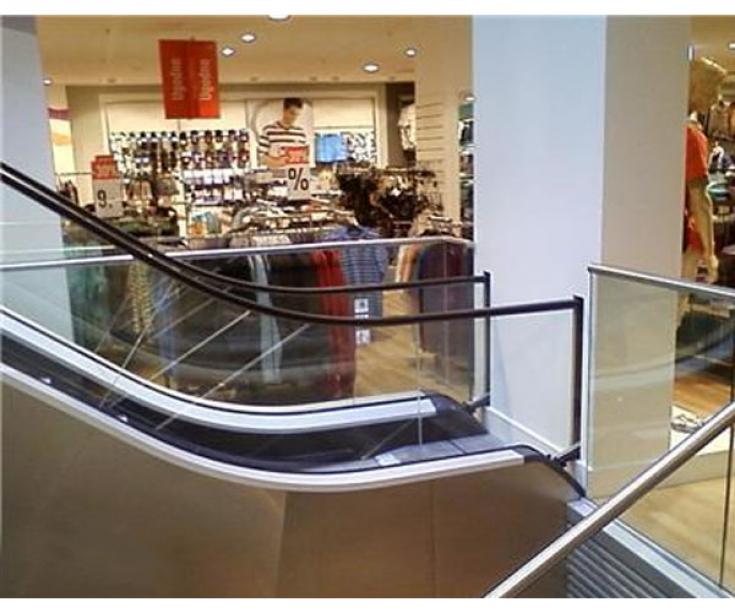 an escalator in a store with a glass railing