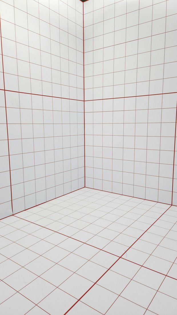 A room with white tiles and red lines on the floor