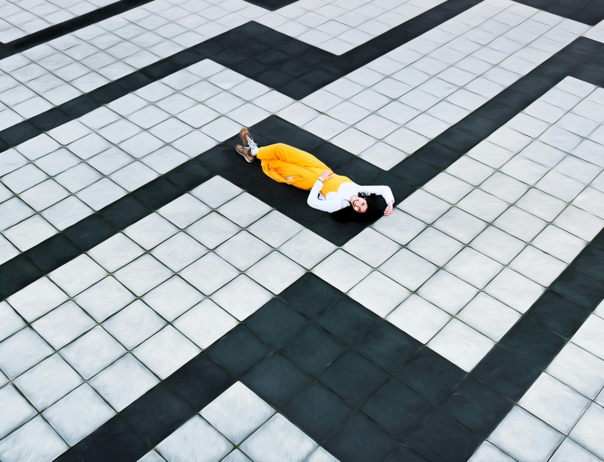 A woman in a yellow dress is laying on the ground in a maze