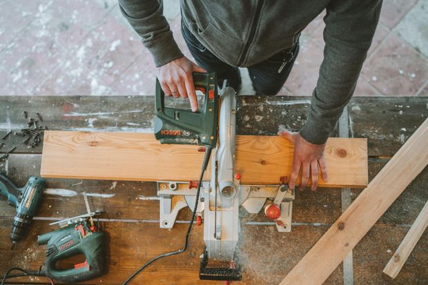 A man is cutting a piece of wood with a circular saw.