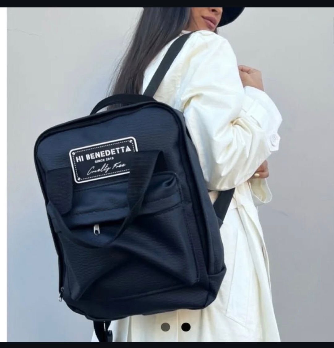 Una mujer con una bata blanca y una mochila negra que dice hola benedetta