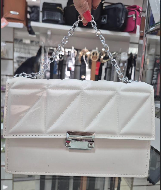 Una persona sostiene un bolso blanco con una cadena de plata.