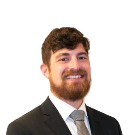 A smiling doctor in a lab coat with a stethoscope around his neck.