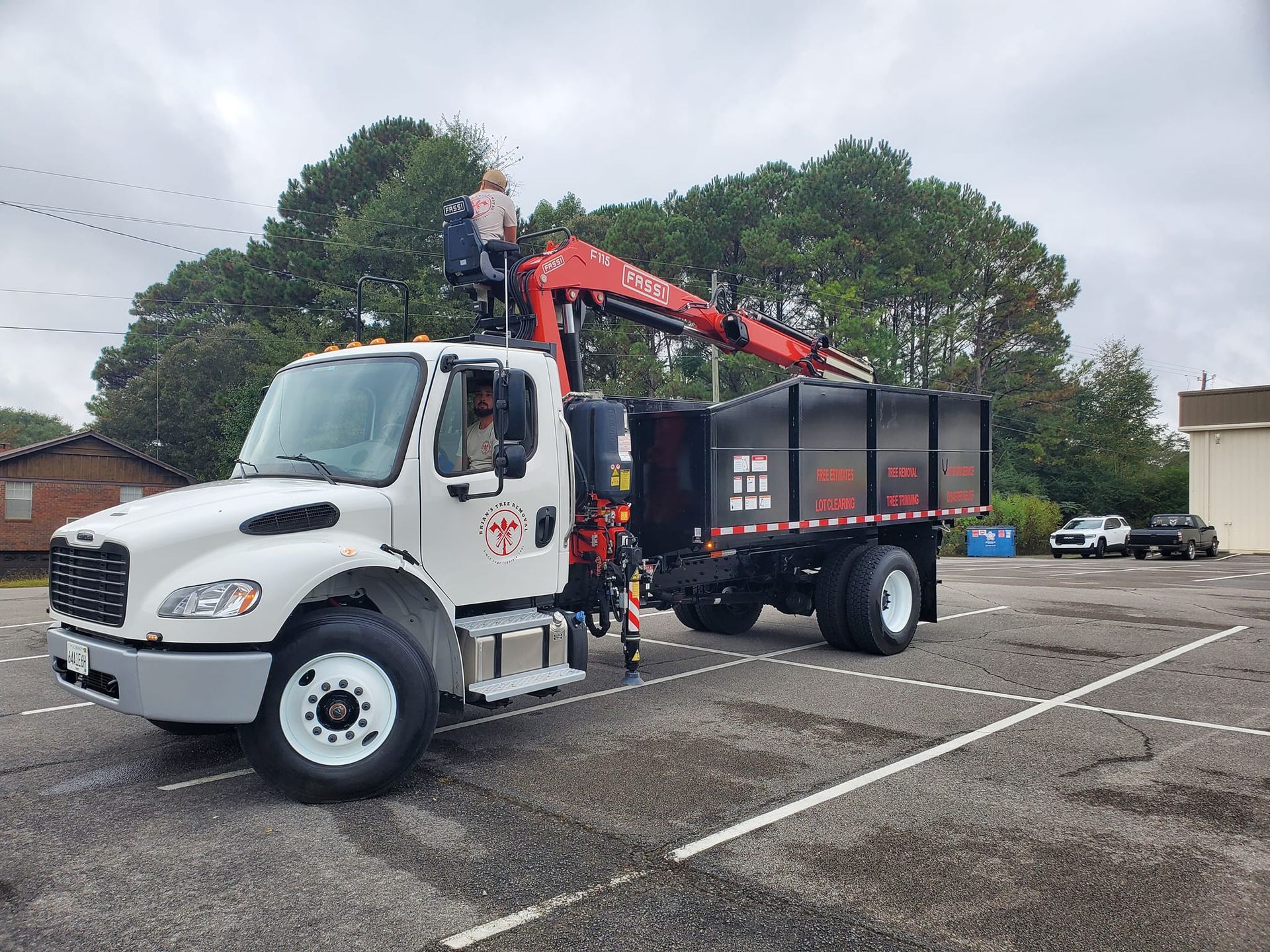 A dump truck with a crane attached to it is parked in a parking lot.