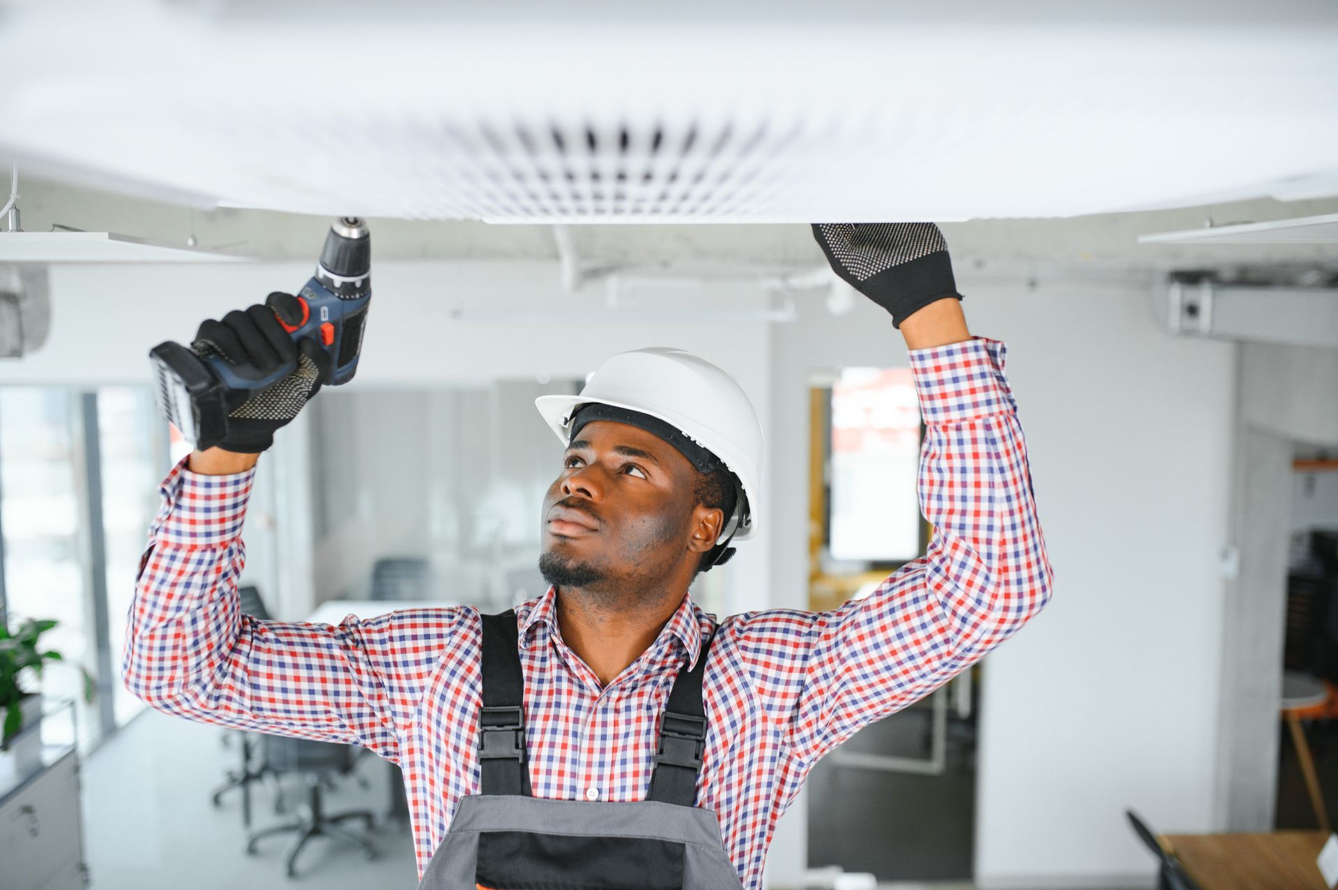 A man is working on a ceiling with a drill.