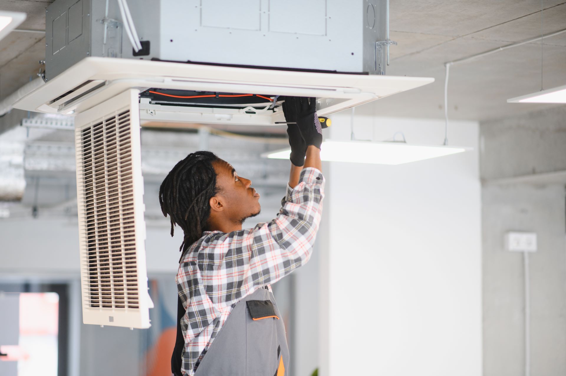 A man is working on an air conditioner in an office.