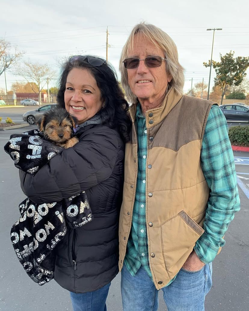 A man and a woman are standing next to each other holding a puppy.