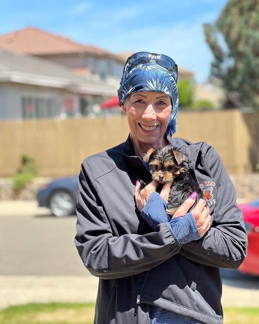 A woman is holding a small dog in her arms.