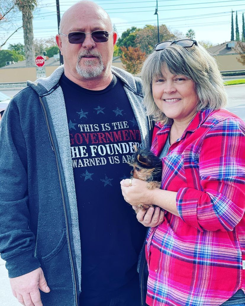 A man and a woman are standing next to each other holding a dog.