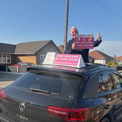 A man is standing on top of a car holding a sign.