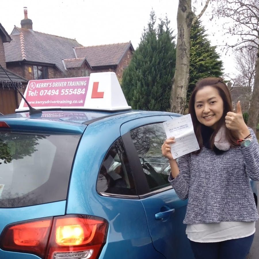 a woman is giving a thumbs up in front of a blue car .