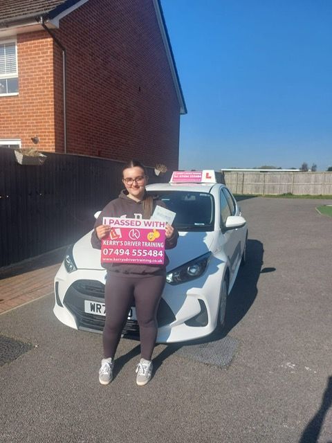 A woman is holding a sign in front of a white car.