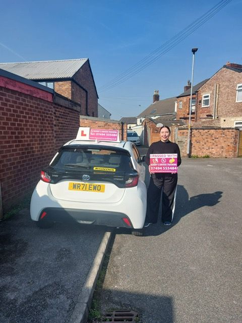 A woman is holding a sign in front of a white car