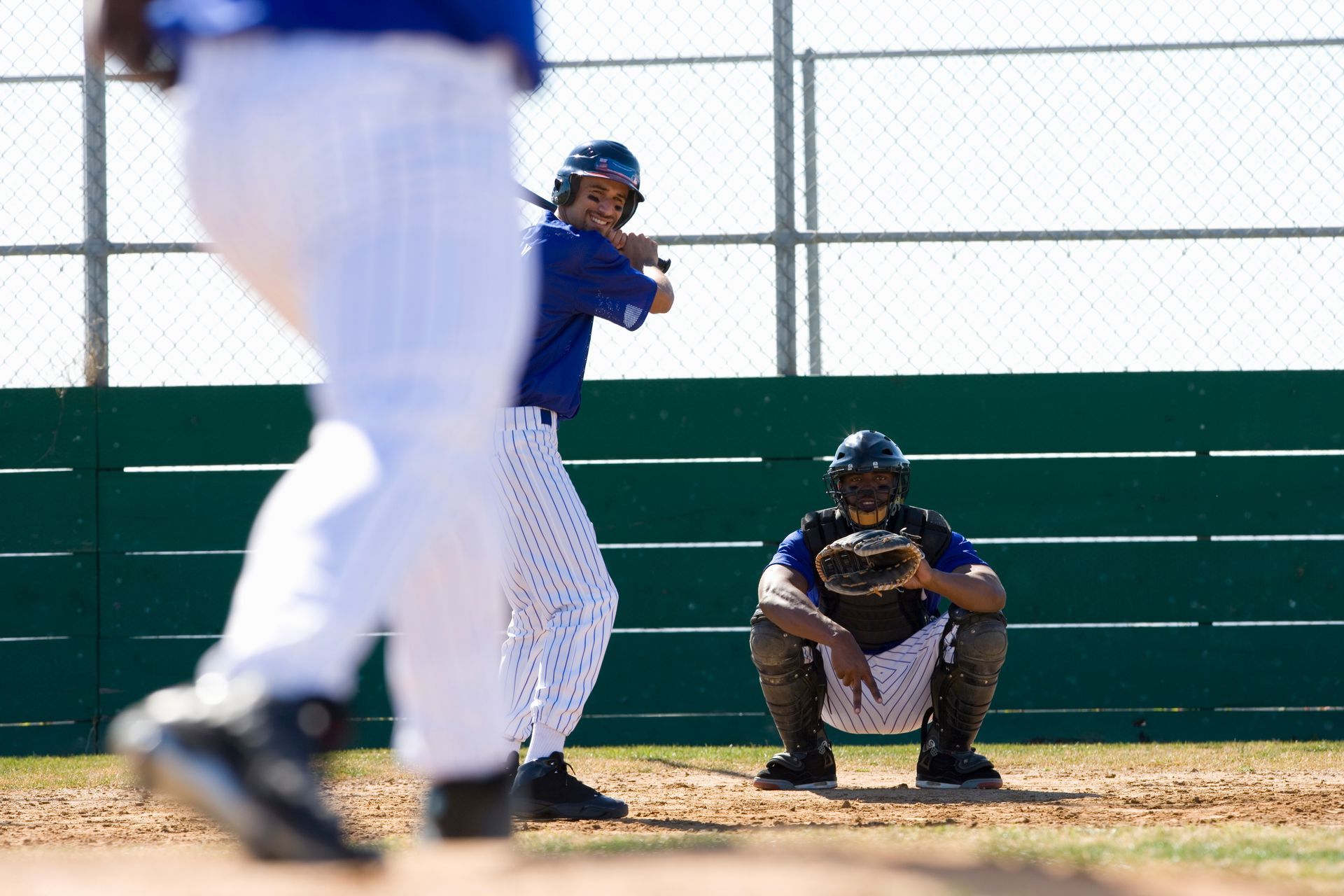 Baseball batter at bat, catcher in crouch, field setting.