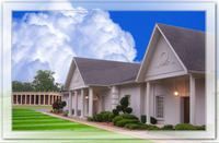 Building with white columns and gray roof under a blue sky with clouds