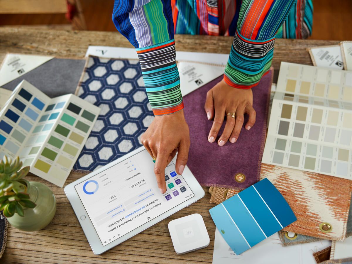 a woman is using a tablet to choose paint colors for a room .