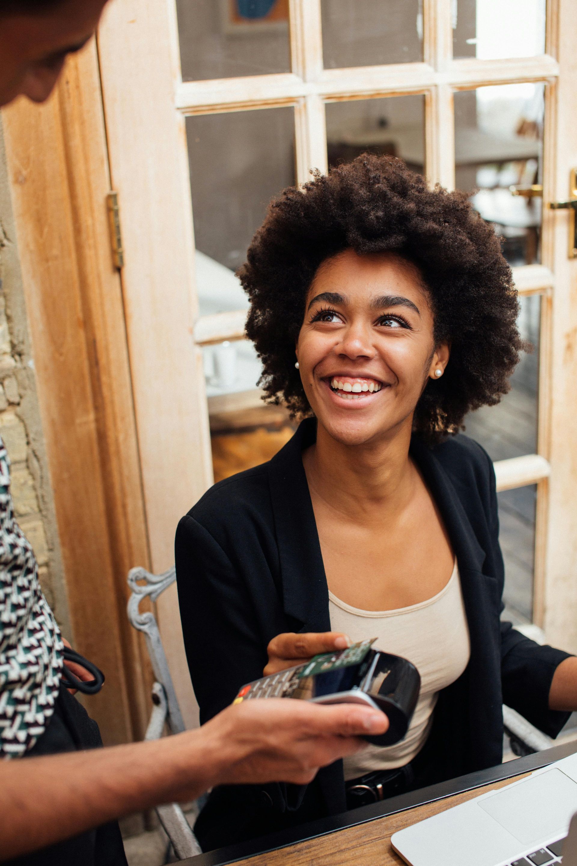 A woman is sitting at a table using a credit card machine.