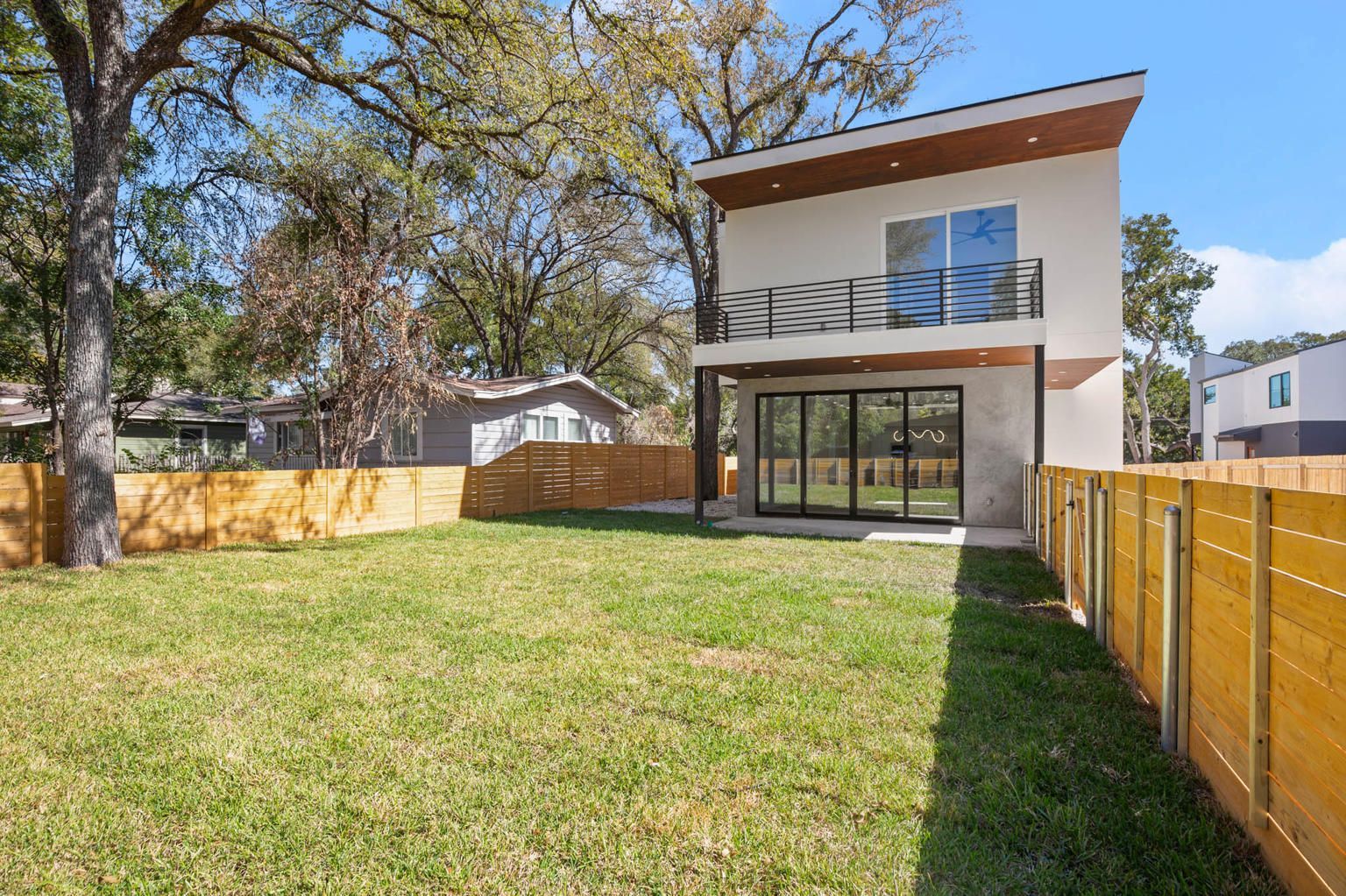 the backyard of a house with a wooden fence and a large lawn .