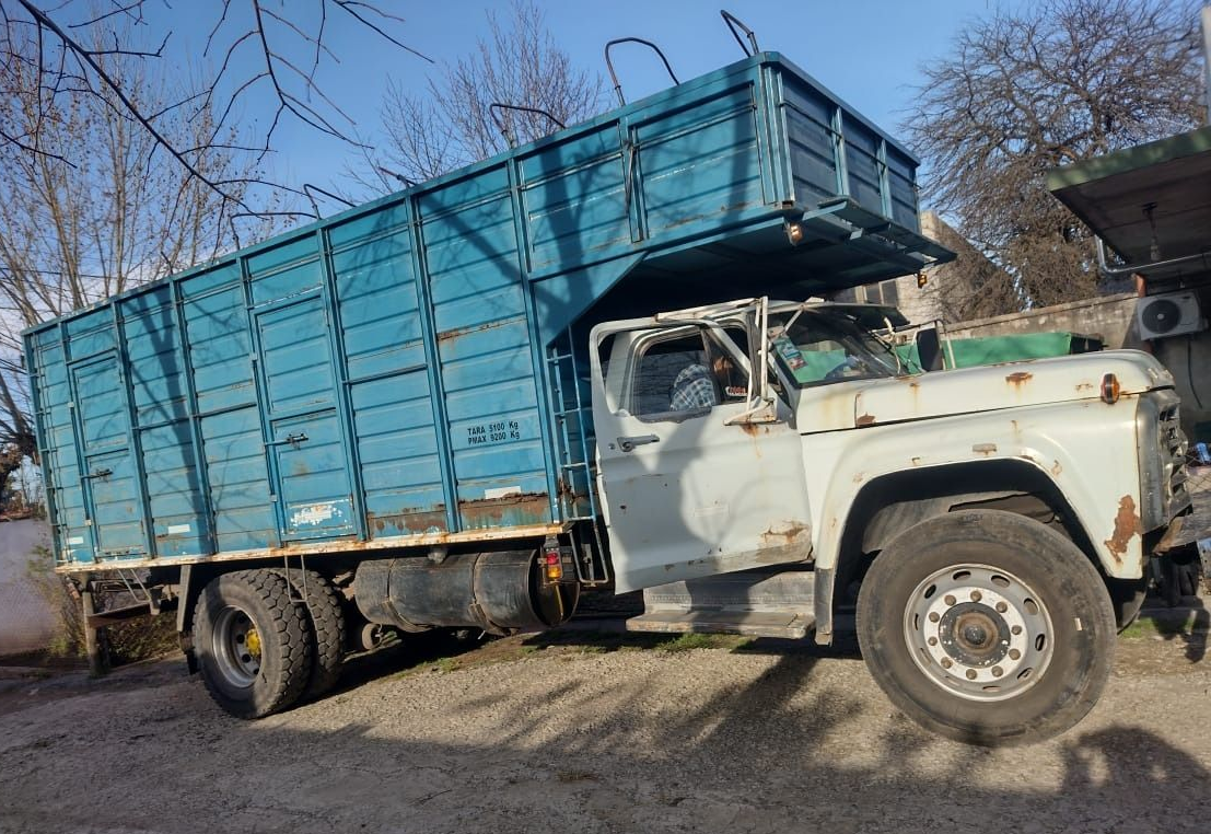 Camión viejo de color azul claro con una gran caja de carga estacionada al aire libre, que muestra signos de óxido.
