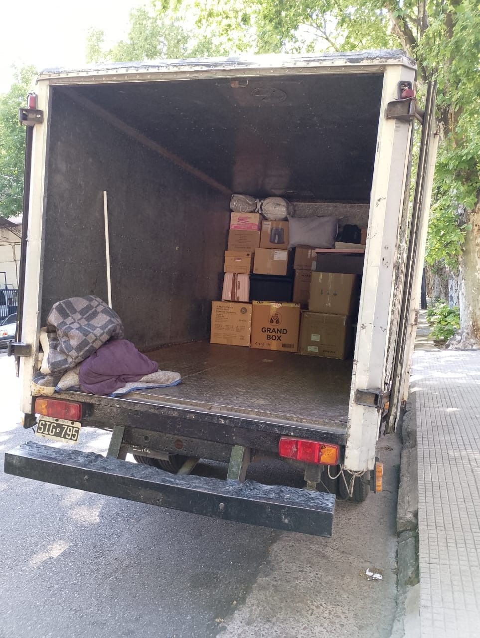 Parte trasera abierta de un camión blanco lleno de cajas y algunas pertenencias personales.