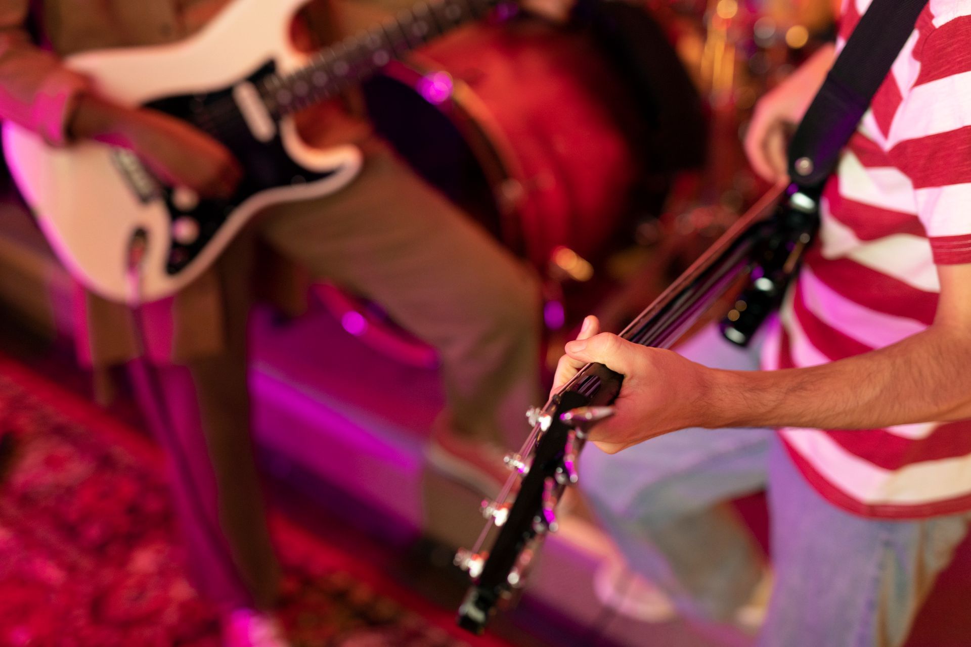 Miembros de la banda tocando guitarras durante una actuación, con camisa de rayas rojas y blancas.