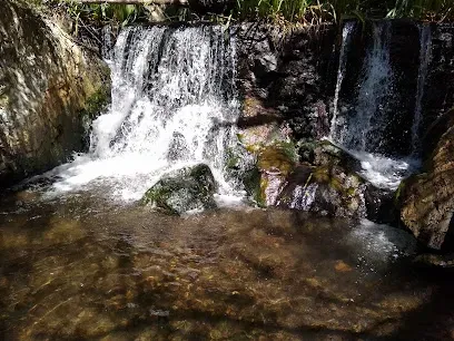Cascading waterfall in Bouquet Canyon, its silver ribbons of water tumbling over mossy boulders into a crystal-clear pool