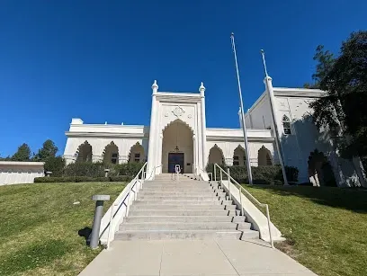 Historic white Mission Revival building at Brand Park, with arched walkways and red-tile roof under clear blue skies
