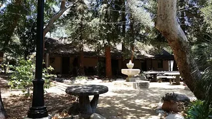 Sun-dappled 1828 adobe hacienda surrounded by native gardens, with rustic stone picnic tables under ancient oak trees