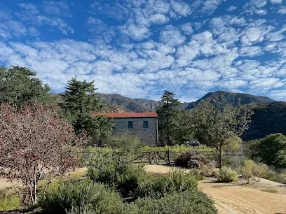 Panoramic view of rugged San Gabriel Mountains from Deukmejian Park, with golden grasslands and oak woodlands under a vast blue sky