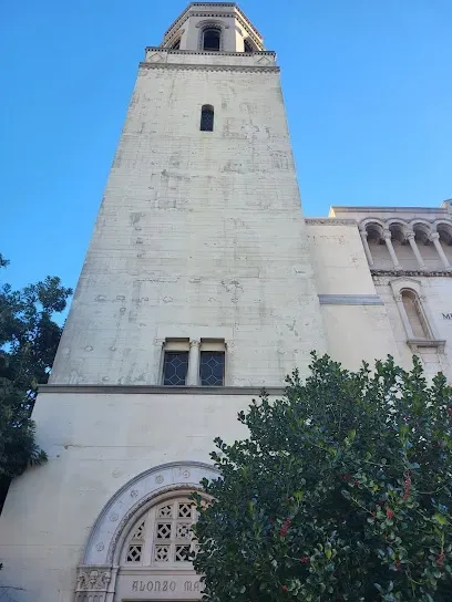 Majestic white castle-like mausoleum at Forest Lawn, its turrets and spires rising above sunlit emerald lawns and flowering gardens