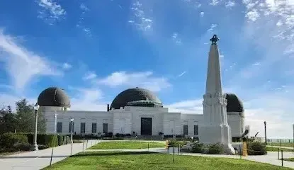 Griffith Observatory, a white building with distinctive round dome, under bright blue skies on a sunny day
