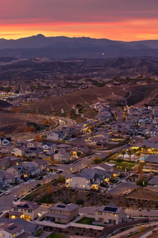 Hard Money Lender Los Angeles - Residential neighborhood at dusk with a view of suburban houses, winding roads, and hills under a colorful sunset sky.