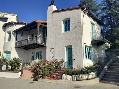 Historic white 1920s ranch house at Hart Park, its wide porch and dormer windows glowing in midday sunlight