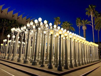 Illuminated Urban Light installation at LACMA with tourists photographing the glowing lamp posts at night