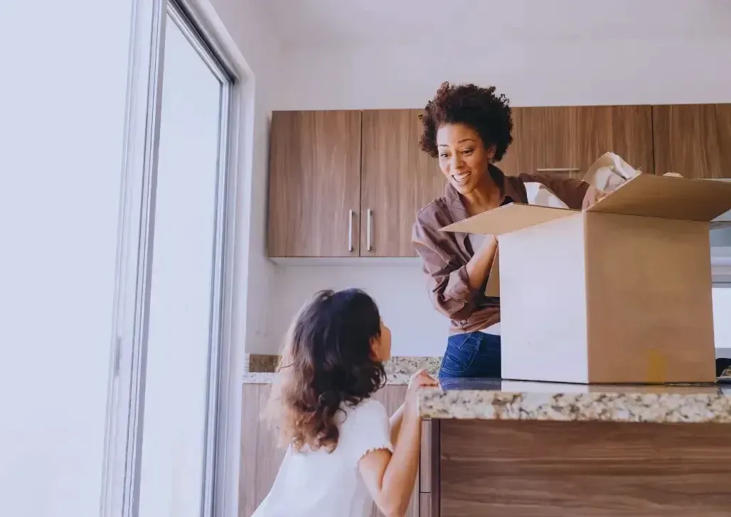Mother and daughter happily unboxing kitchenware together in a sunny kitchen