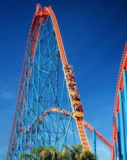 Twisted Colossus roller coaster's towering red tracks looping against a blue sky at Six Flags Magic Mountain