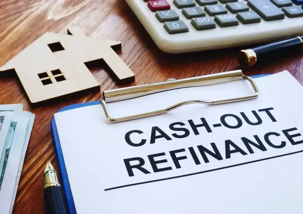 Refinance loan paperwork on table with signed documents, a pen, and miniature house model