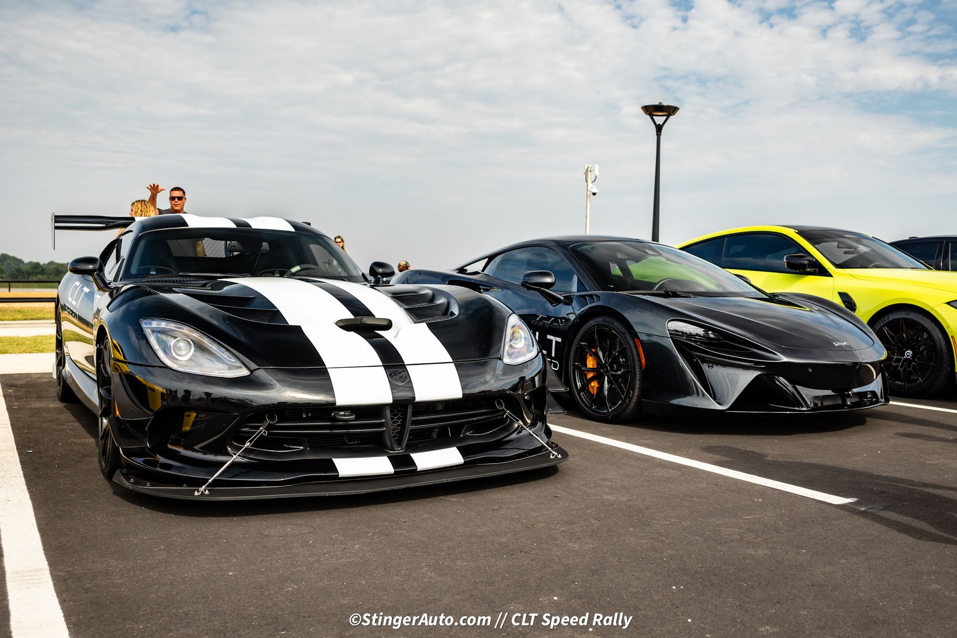 A black and white sports car is parked next to other sports cars