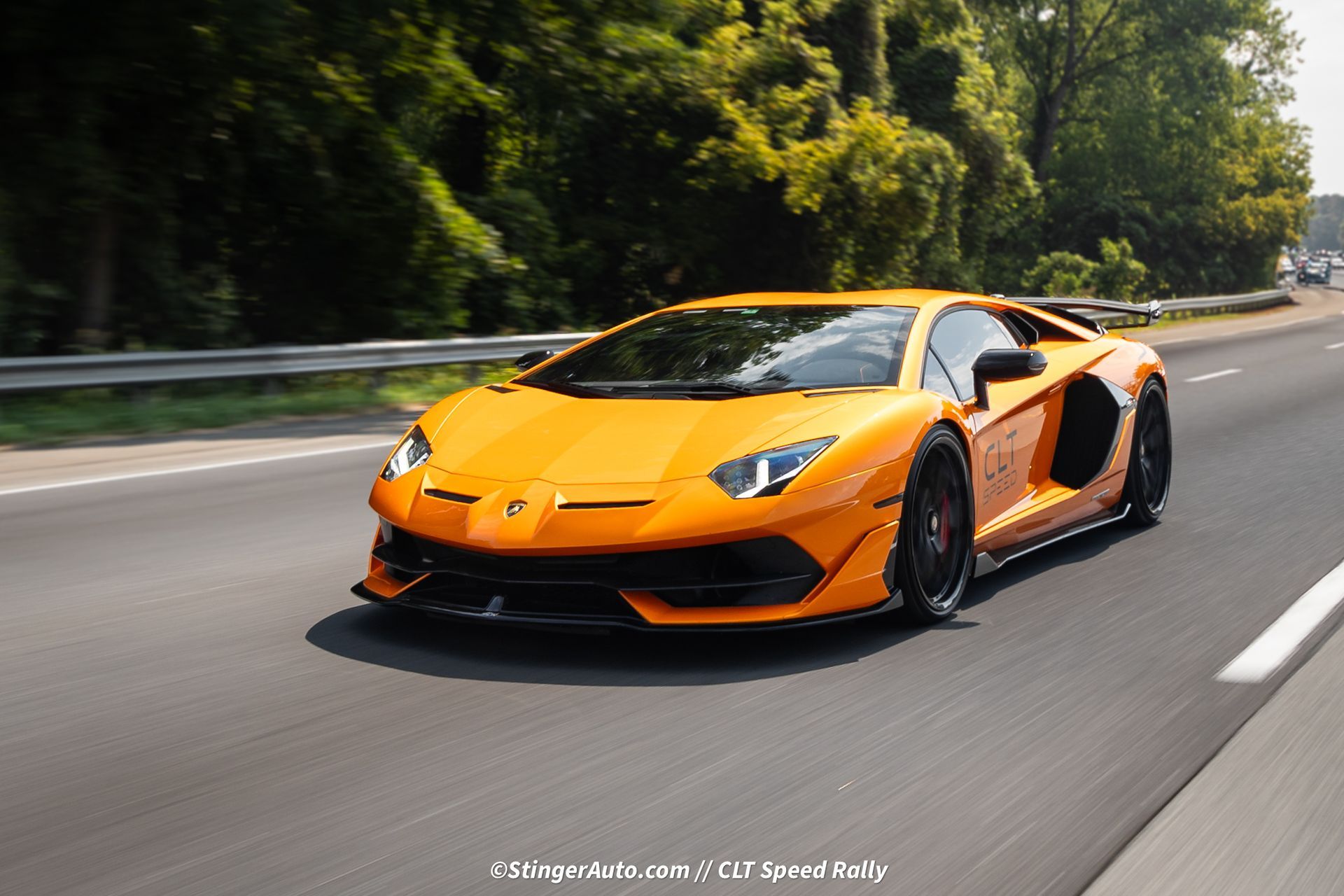 An orange lamborghini aventador is driving down a highway