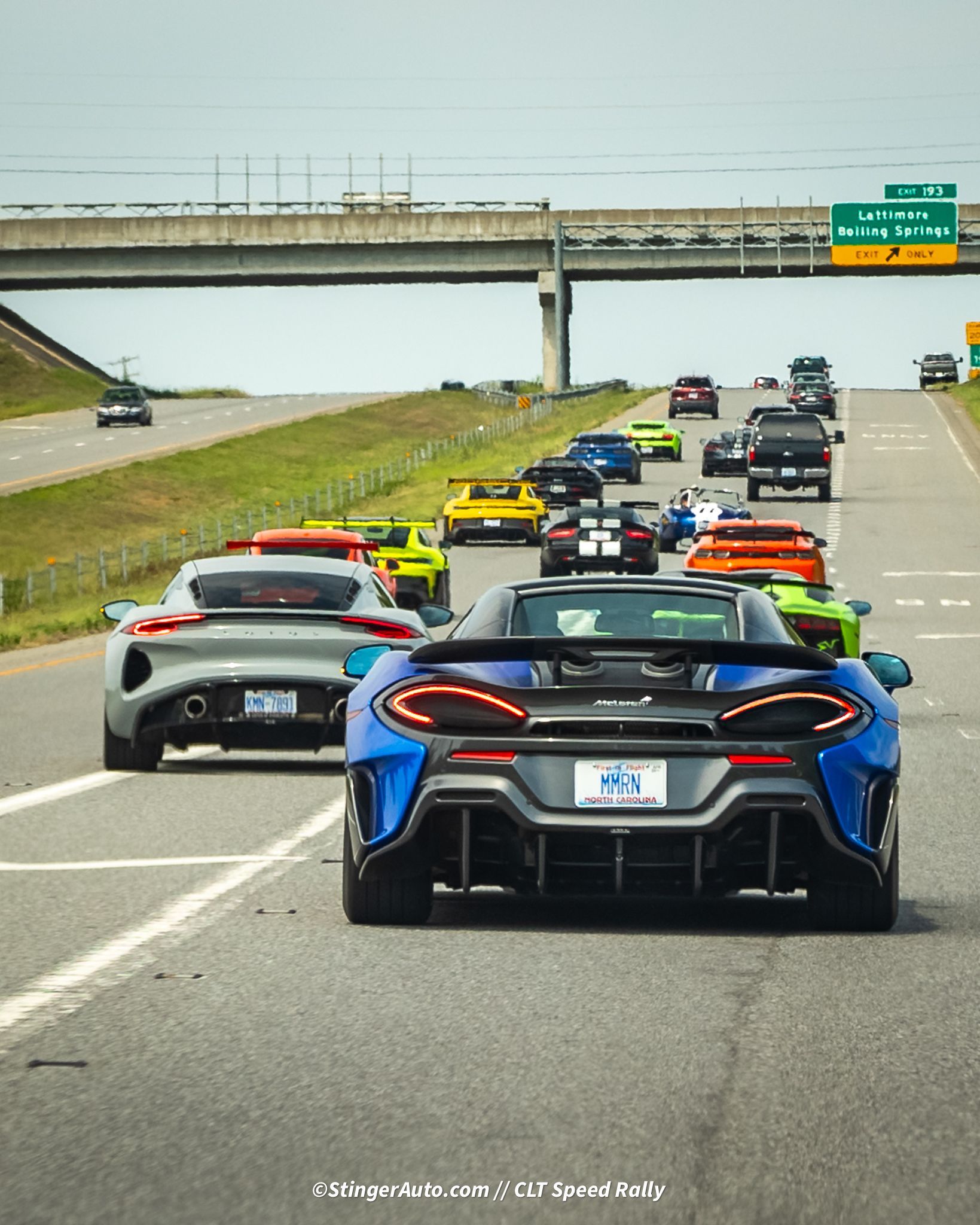 A row of cars are driving down a highway