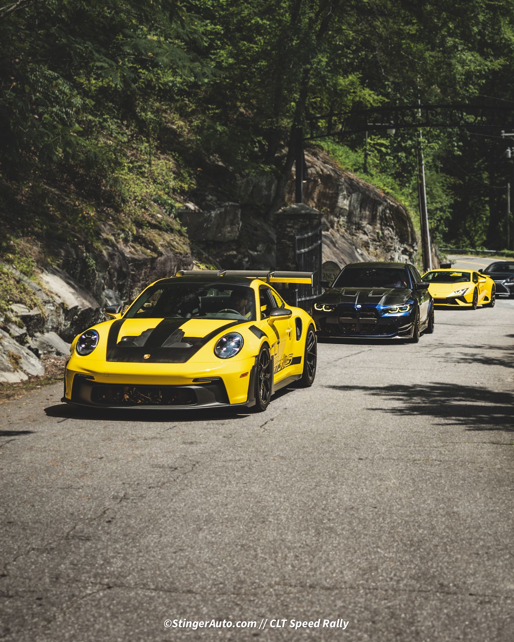 A row of sports cars are driving down a road