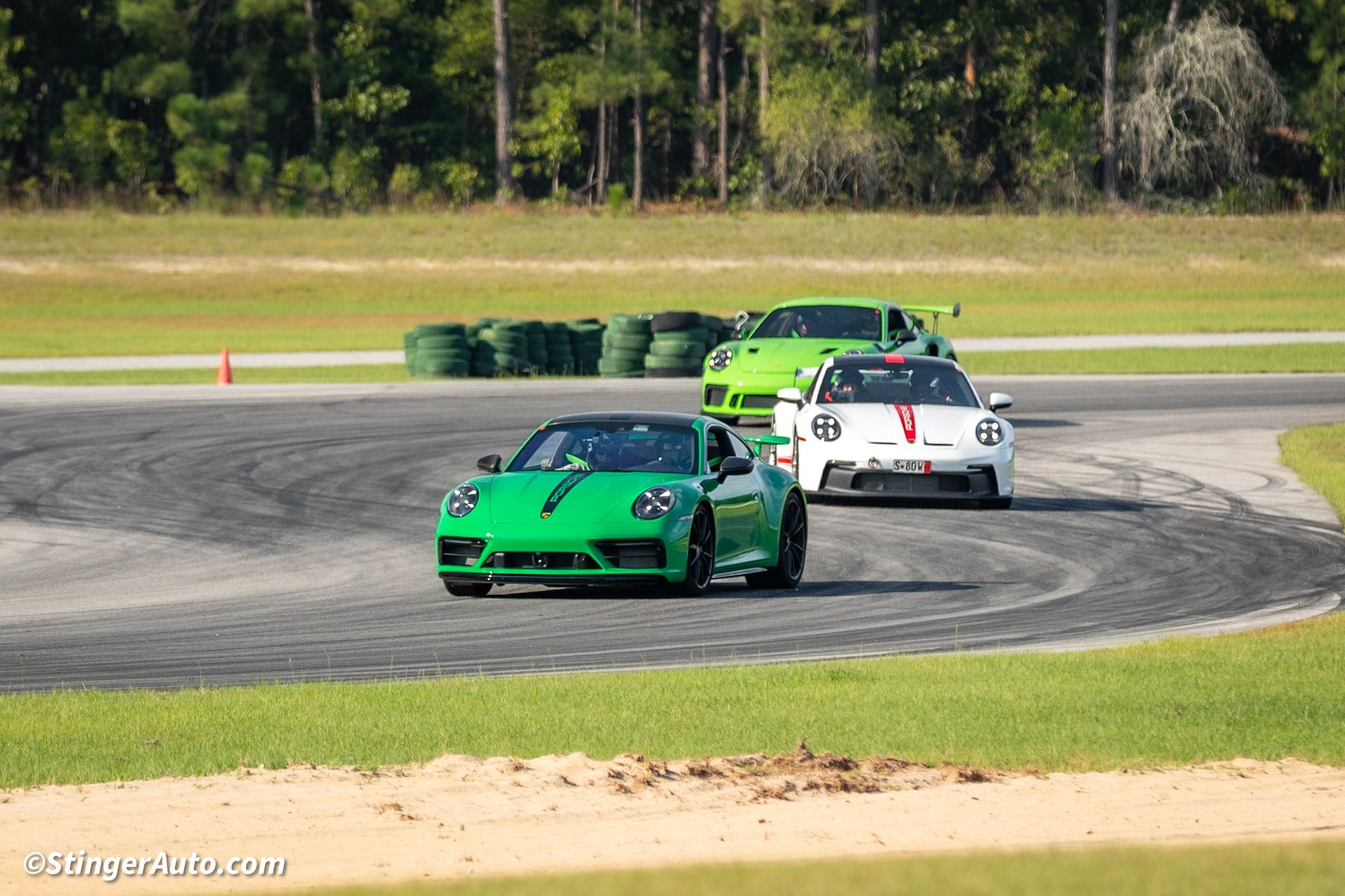 A green sports car is driving on a track with other cars