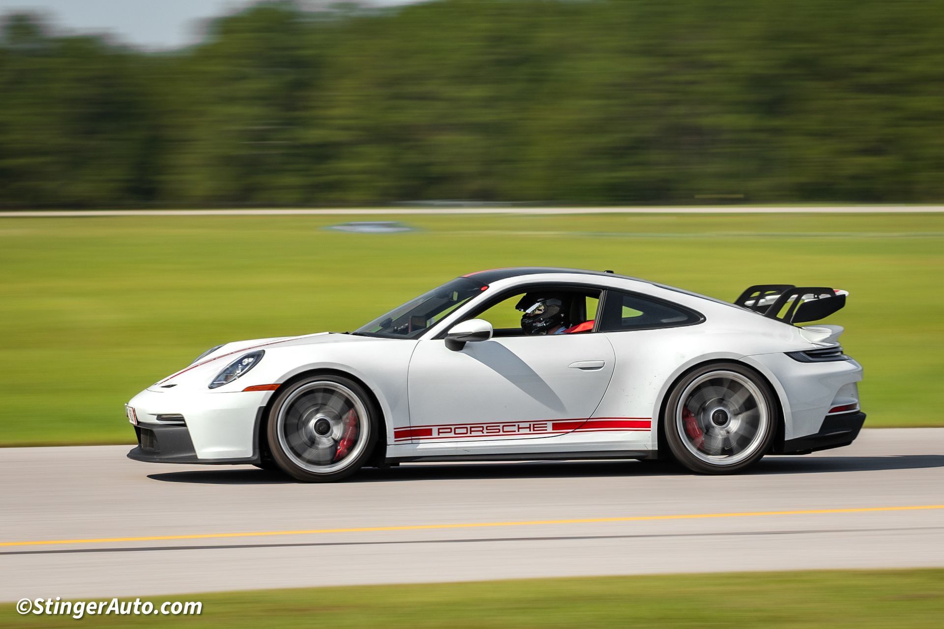 A white sports car is driving down a road