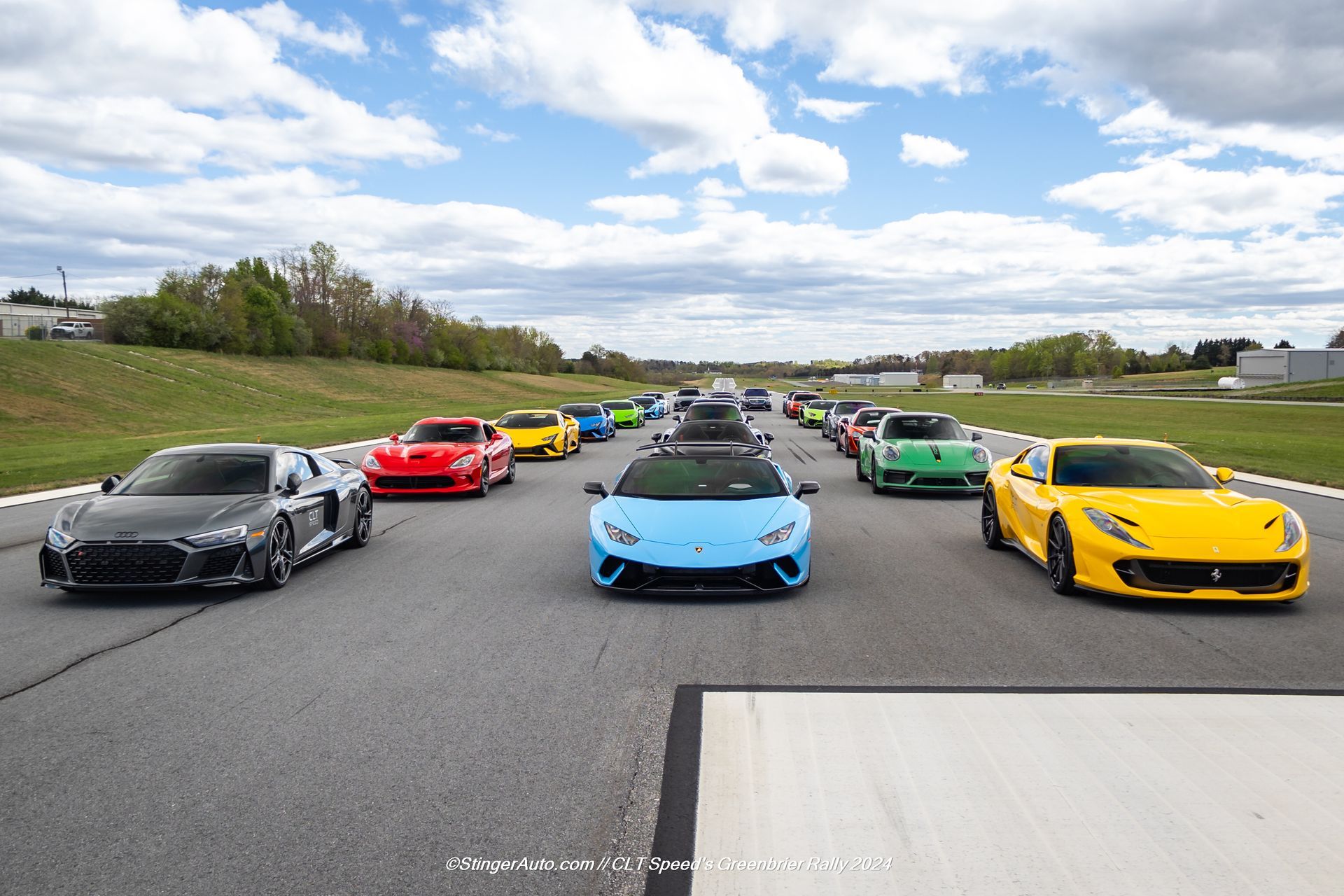 A row of sports cars are driving down a road