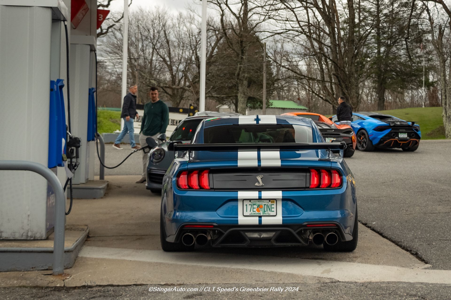 A blue ford mustang is parked at a gas station